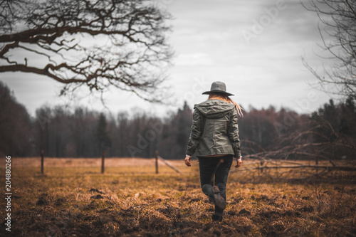 Rural scene with woman in hat walking on field, melancholic autumn mood © leszekglasner