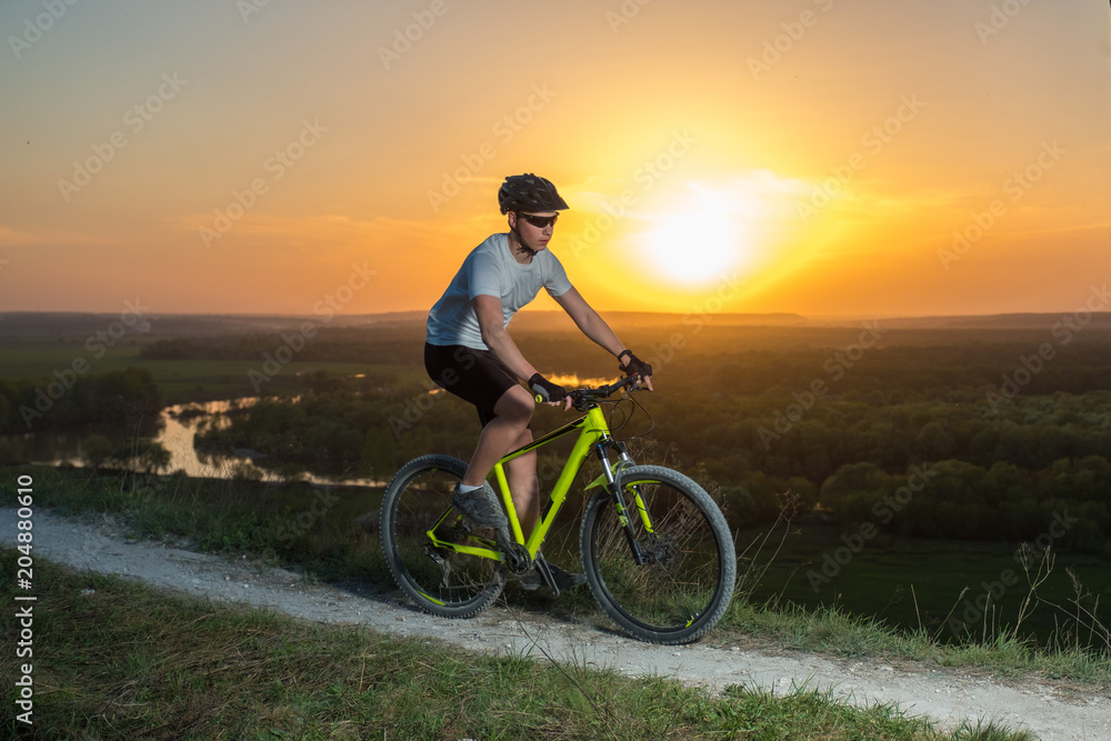 A cyclist in a white T-shirt rides a bike along the mountain path. The concept of extreme sports. Mountain bike. A cyclist in a white T-shirt rides a bike along the mountain path. The concept of extreme sports. Mountain bike.