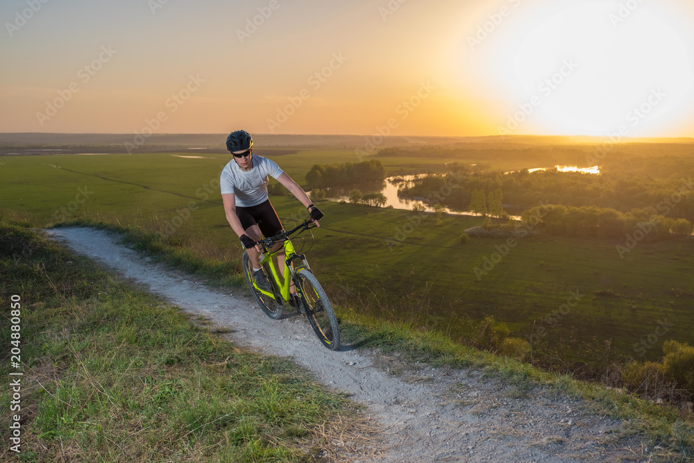 A cyclist in a white T-shirt rides a bike along the mountain path. The concept of extreme sports. Mountain bike. A cyclist in a white T-shirt rides a bike along the mountain path. The concept of extreme sports. Mountain bike.
