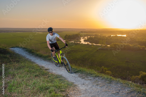 A cyclist in a white T-shirt rides a bike along the mountain path. The concept of extreme sports. Mountain bike.