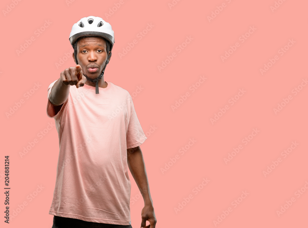 Black man wearing bike helmet pointing to the front with finger Black man wearing bike helmet pointing to the front with finger