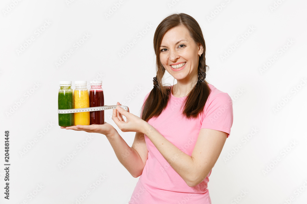 Woman holds row of green, red, yellow detox smoothies in bottles, measure tape isolated on white background. Proper nutrition, vegetarian drink, healthy lifestyle, dieting concept. Copy space, flack. Woman holds row of green, red, yellow detox smoothies in bottles, measure tape isolated on white background. Proper nutrition, vegetarian drink, healthy lifestyle, dieting concept. Copy space, flack.