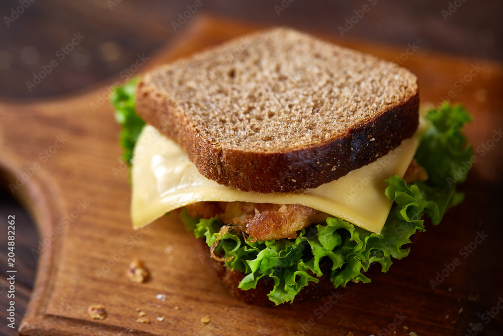Tasty and fresh sandwiches on cutting board over a dark wooden background, close-up Tasty and fresh sandwiches on cutting board over a dark wooden background, close-up