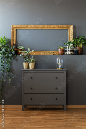 Billede på lærred Golden frame above gray dresser