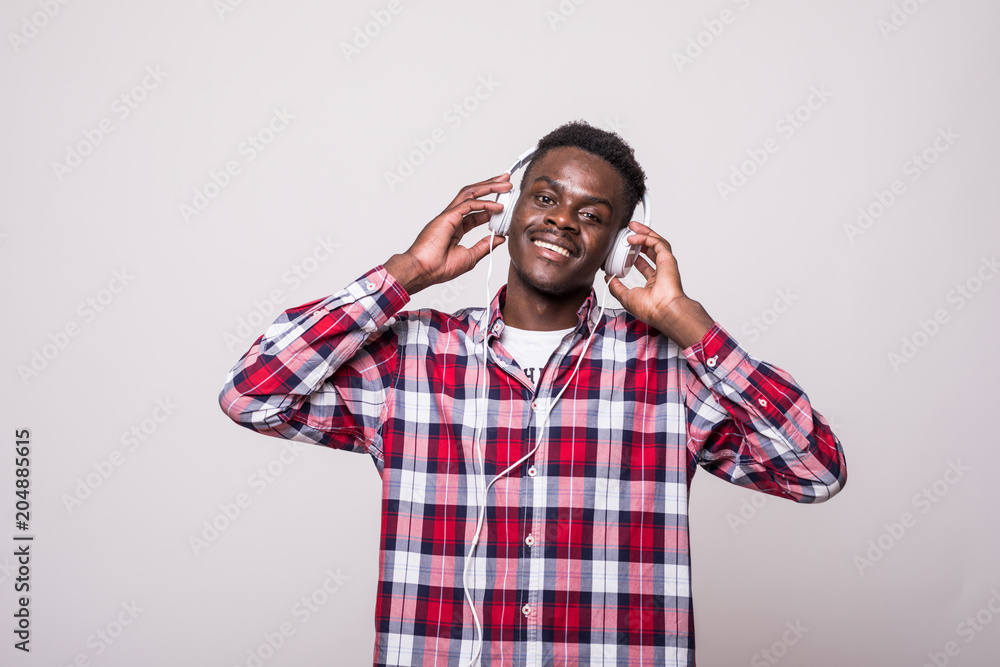 Portrait of a cheerful young afro american man listening to music with headphones and singing isolated over white background Portrait of a cheerful young afro american man listening to music with headphones and singing isolated over white background