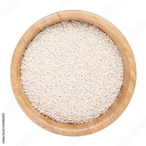 White sesame seeds in wooden bowl isolated on white. Top view.