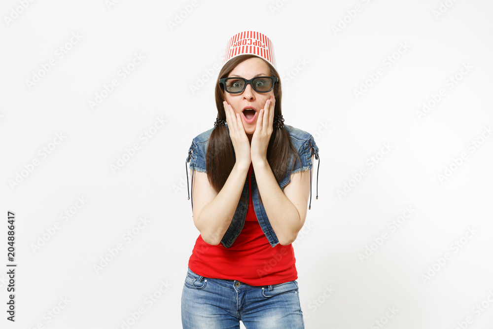 Portrait of young shocked attractive woman in 3d glasses and casual clothes with bucket for popcorn on head watching movie film and clinging to face isolated on white background. Emotions in cinema. Portrait of young shocked attractive woman in 3d glasses and casual clothes with bucket for popcorn on head watching movie film and clinging to face isolated on white background. Emotions in cinema.