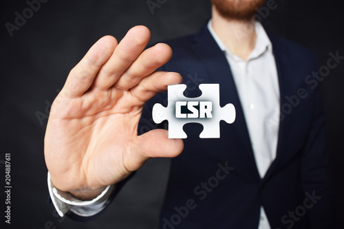 Businessman holding a puzzle with the inscription:CSR