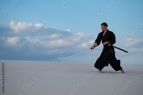Concentrated man is practicing martial arts in the desert