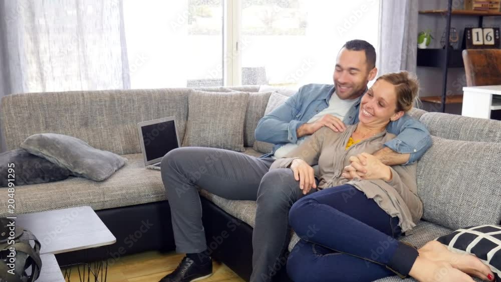 beautiful young couple man and woman at home relaxed on sofa watching tv beautiful young couple man and woman at home relaxed on sofa watching tv