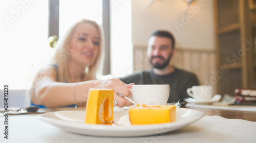Sweet dessert in front of couple sitting in a cafe drinks coffee and laughing
