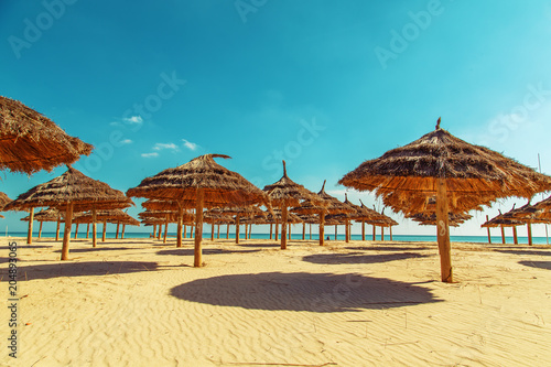 Fototapeta Naklejka Na Ścianę i Meble -  Straw umbrellas on the beach on a sunny day.