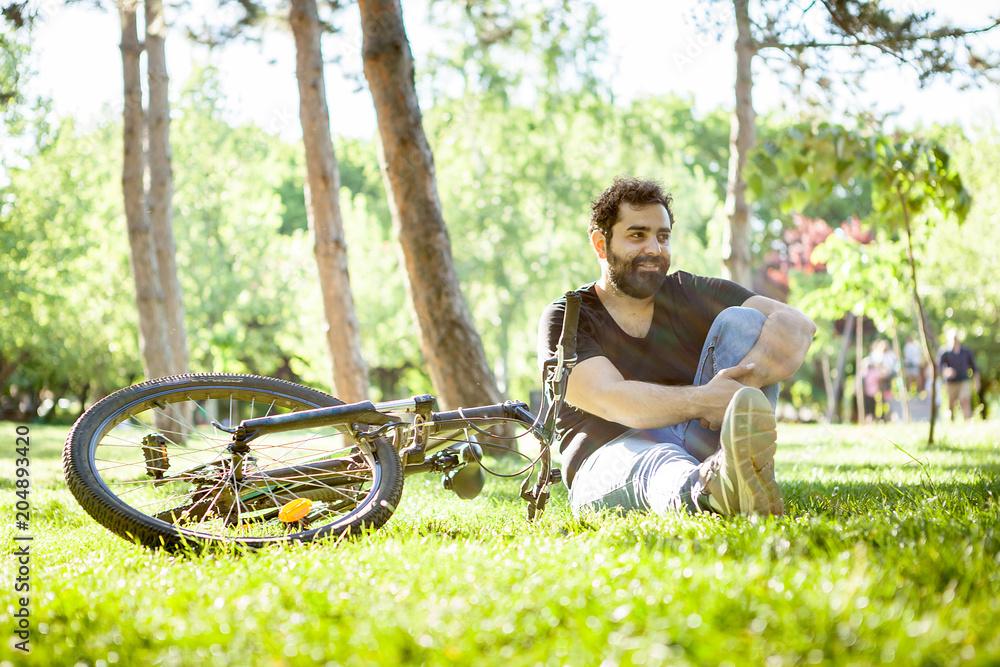Bearded man looking away from the camera with his bicycle next to him in the park. Sport and health Bearded man looking away from the camera with his bicycle next to him in the park. Sport and health