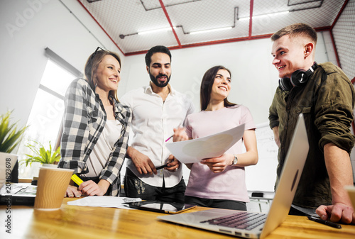 Team of office workers discussing diagrams before flip chart board, indoor shot in modern office