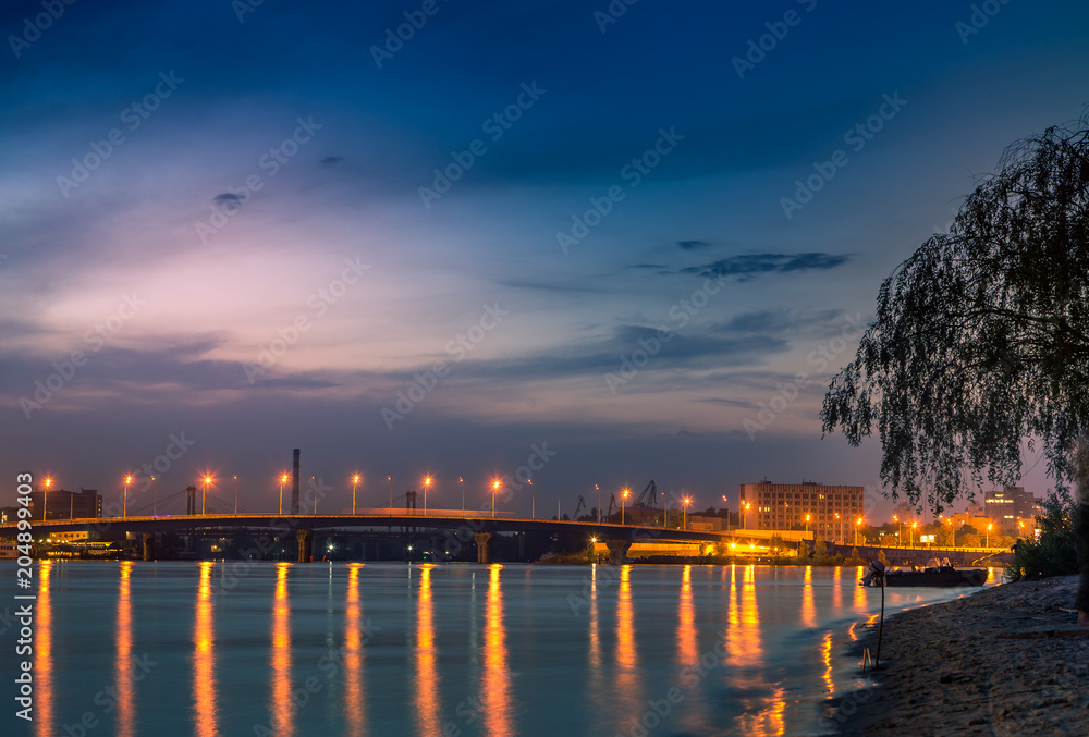 Obraz premium beautiful background sunset on the river with views of the illuminated lights Bridge