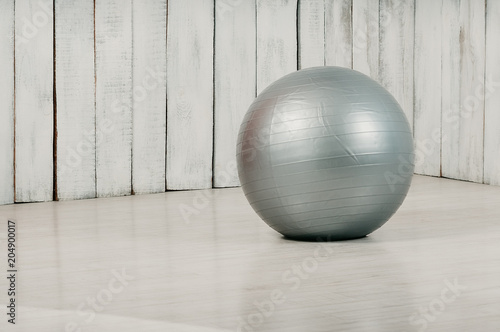 Grey fitball in a gym  light floor and background