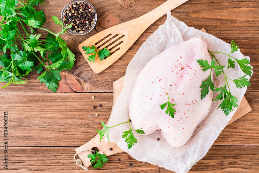 Raw chicken breast on a frame in spices and herbs on a cutting board on a wooden table. Top view Raw chicken breast on a frame in spices and herbs on a cutting board on a wooden table. Top view