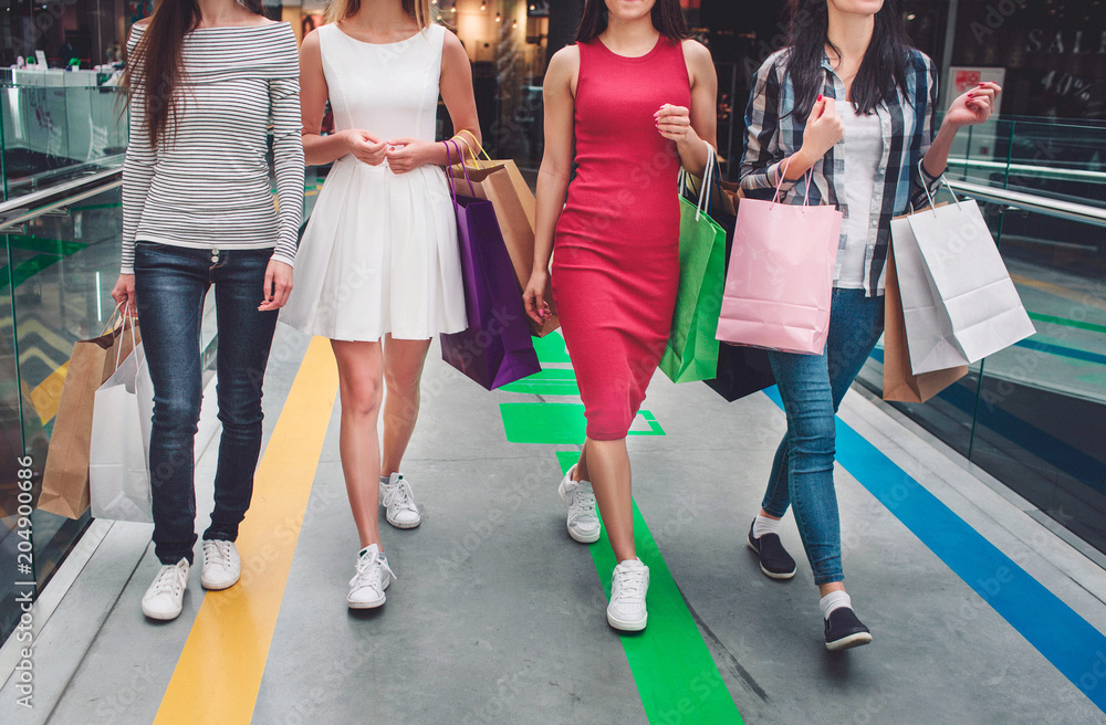 Cut view of girls walking together in a big store. They wear