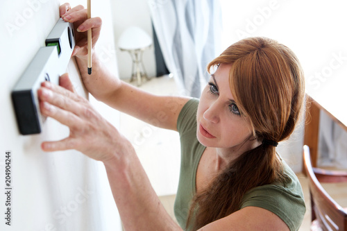 Mature woman marking on wall with level
