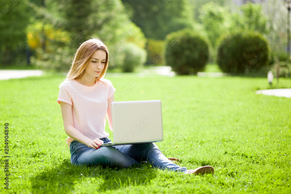 girl with a laptop sitting on the lawn girl with a laptop sitting on the lawn