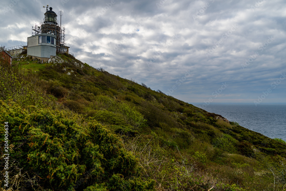Kullaberg, Sweden - Kullen lighthouse on a hilltop on a dark and cloudy day just after a rainfall. The lighthouse is being renovated and scaffoldings surround it.