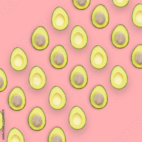 Avocado halves pattern isolated on pink background, top view conceptual image with space for text.