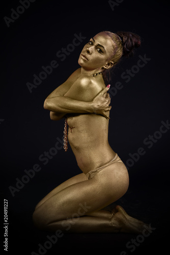 woman fully dressed in gold on black background