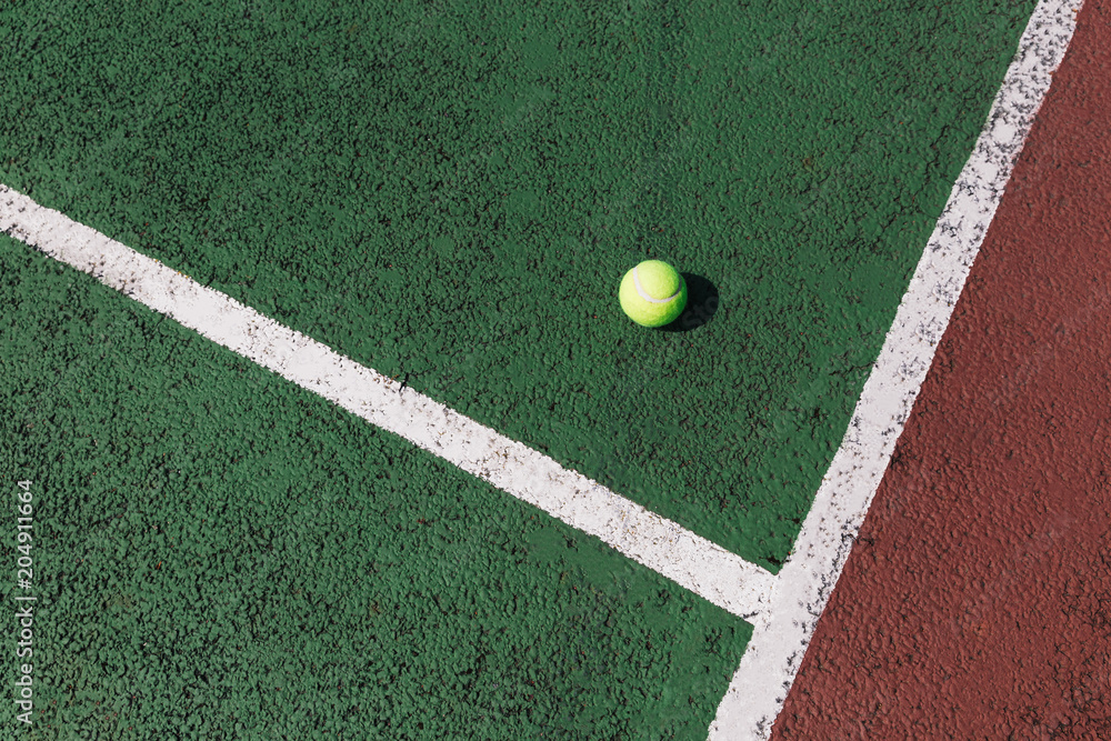 Yellow tennis ball on green tennis court