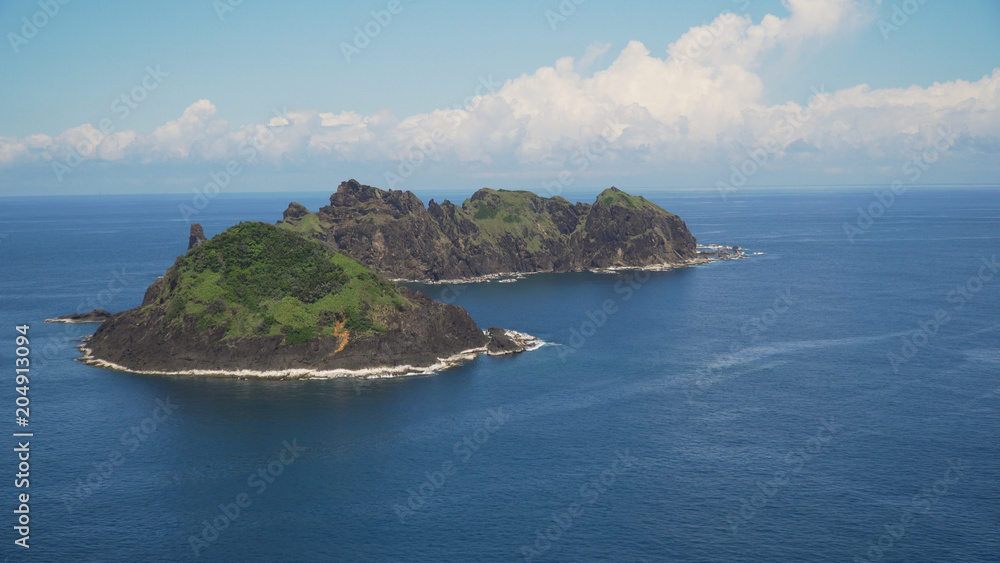 Small rocky islands in the sea, blue sky and clouds. Dos Hermanas, Palau, Santa Ana. Seascape with tropical islands in the ocean.
