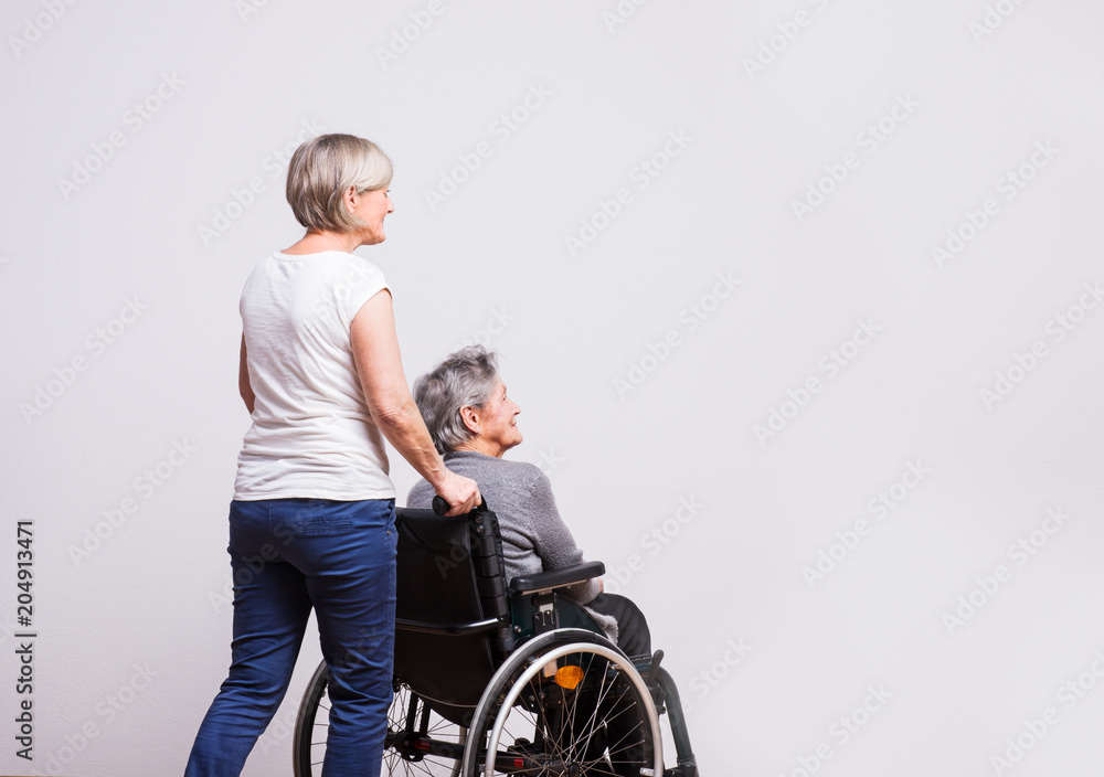 Studio portrait of a senior woman in wheelchair with a carer. Studio portrait of a senior woman in wheelchair with a carer.