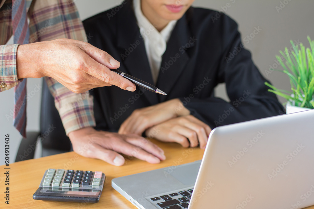 business man points to a computer explaining something to a female businesswoman in an office. business man points to a computer explaining something to a female businesswoman in an office.