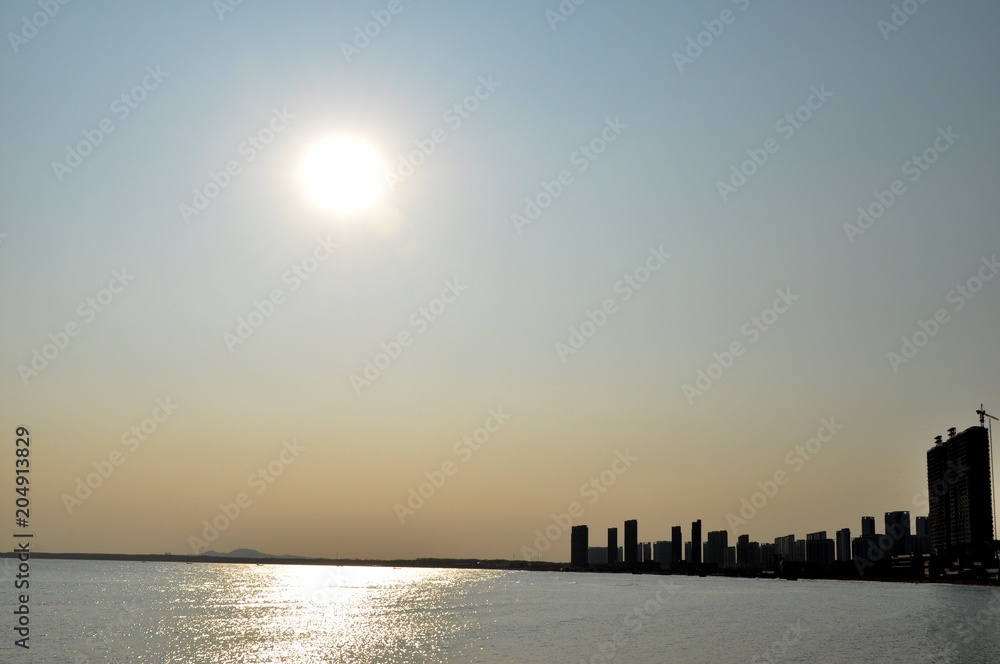 Sunset over the sea and the city Sunset over the sea and the city