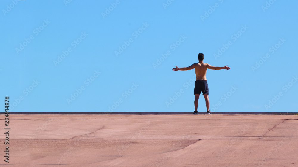 Young man, athlete with open arms against a blue sky. Empty copy space for Editor's text. Young man, athlete with open arms against a blue sky. Empty copy space for Editor's text.