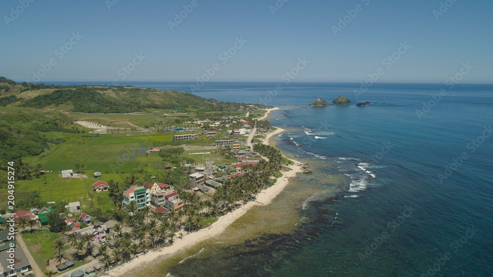 Aerial view of beautiful tropical beach with turquoise water in blue lagoon, Pagudpud, Philippines. Ocean coastline with sandy beach. Tropical landscape in Asia.