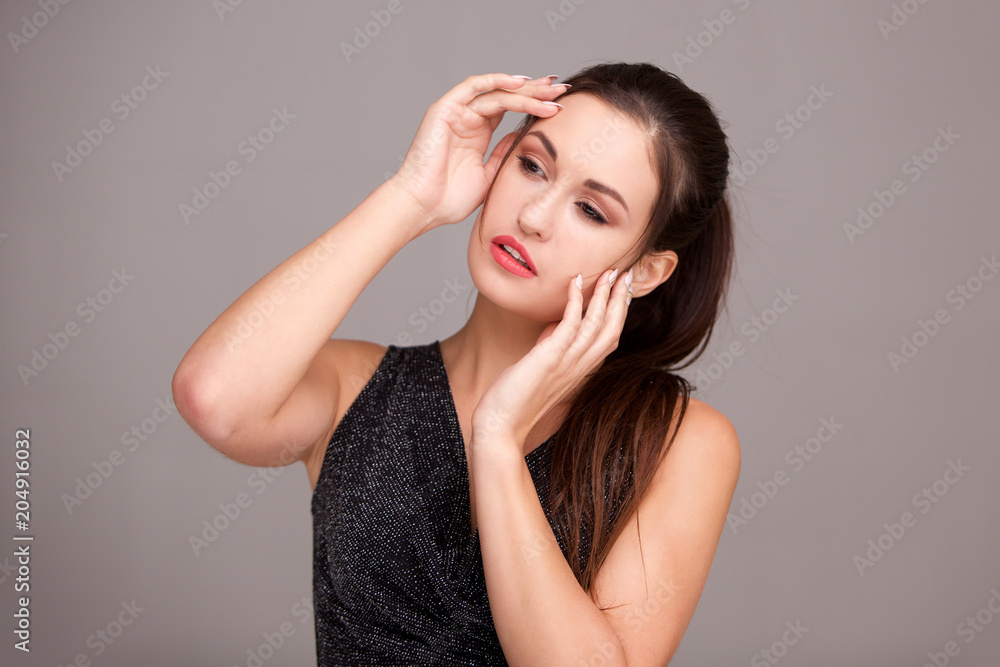 elegant young woman against gray background with hands on face elegant young woman against gray background with hands on face