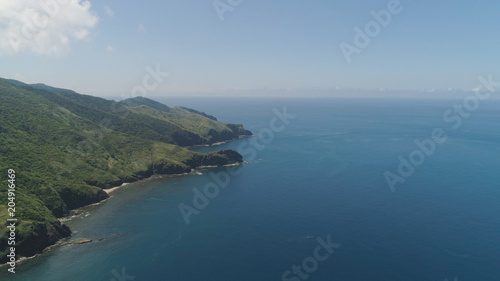Coast of a tropical island Palau with mountains covered with rainforest and trees. Santa Ana, Philippines. Aerial view of island with wild beaches.