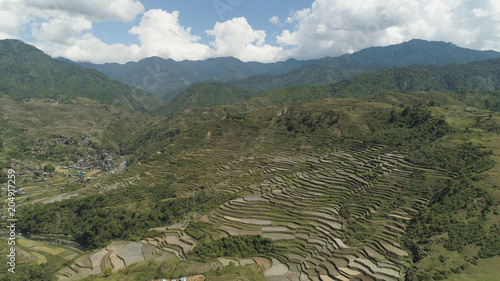 Aerial view of rice terraces and agricultural land on the slopes of the mountains. Village of farmers near rice fields in mountain valley. Mountains covered forest  trees. Cordillera region. Luzon