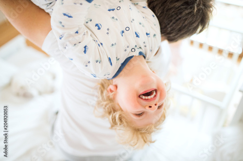 Father holding a happy toddler boy upside down.