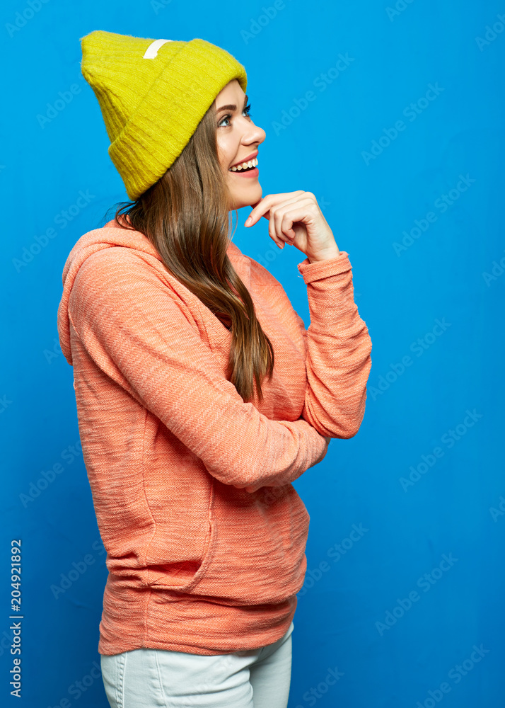 Portrait of casual dressed girl sanding sideways on blue backgro Portrait of casual dressed girl sanding sideways on blue backgro