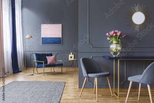 Fototapeta Naklejka Na Ścianę i Meble -  Pink flowers on table in grey elegant living room interior with gold mirror and painting