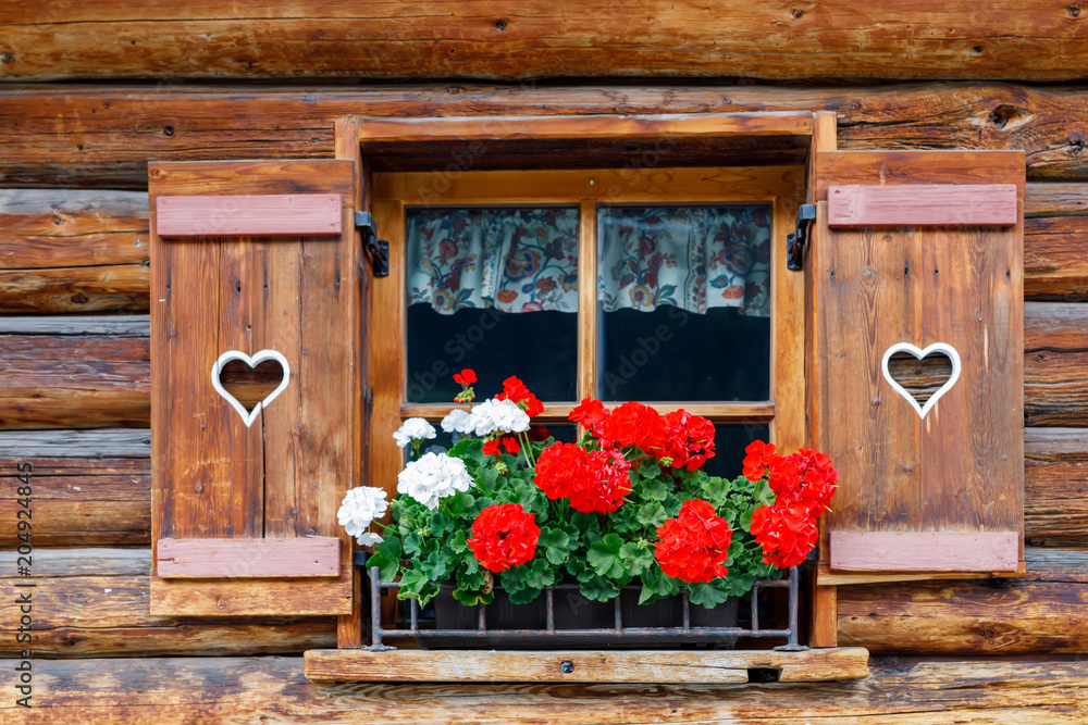 Typical bavarian or austrian wooden window with red geranium flowers on  house in Austria or Germany Stock Photo | Adobe Stock