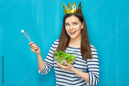 Smiling girl wearing paper golden crown eating dieting food sala