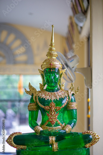 Jade Buddha with Green and Gold sitting on blurred Background