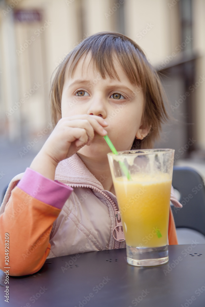 Little beautiful girl child drinks orange. (Vitamins, health, thirst, happy childhood concept) Little beautiful girl child drinks orange. (Vitamins, health, thirst, happy childhood concept)