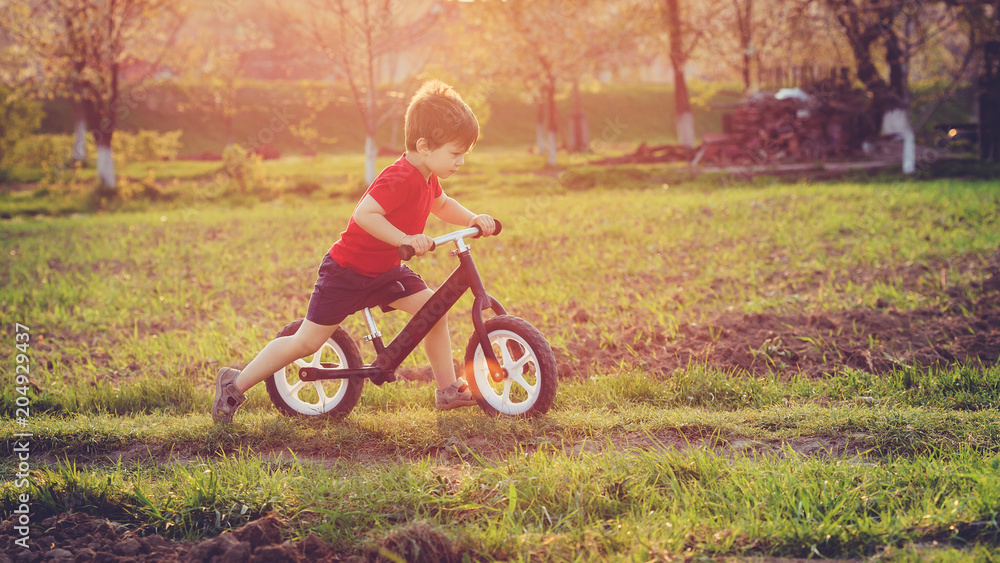 Boy rides a balance bike in the countryside Boy rides a balance bike in the countryside