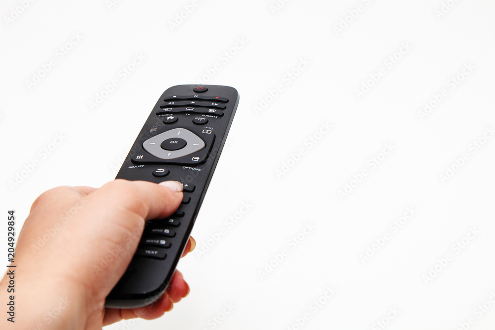 Female hand holding a remote for a TV set on a white background Female hand holding a remote for a TV set on a white background