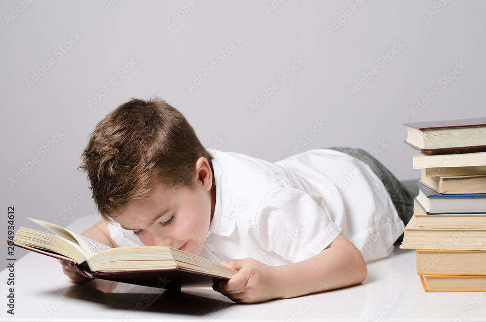Ein Kind liest liegend ein Buch und wirkt interessiert Ein Kind liest liegend ein Buch und wirkt interessiert