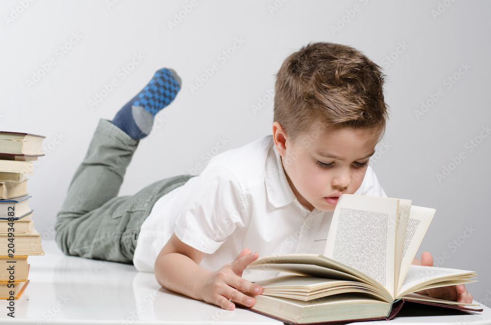 Ein Kind liest liegend ein Buch und wirkt müde Ein Kind liest liegend ein Buch und wirkt müde
