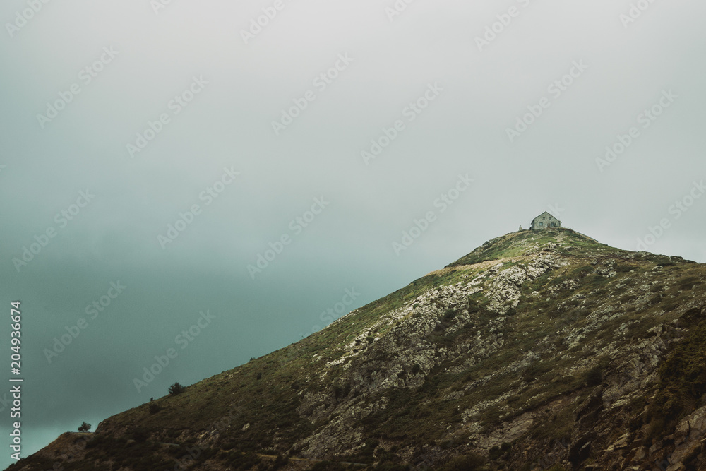 stone house on top of a mountain peak on a cloudy day stone house on top of a mountain peak on a cloudy day