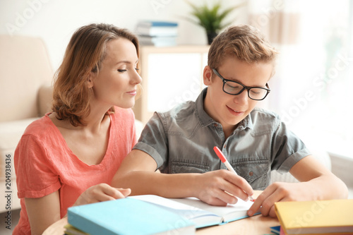 Teenager with mother doing homework at home